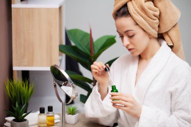 Sevimli kız banyoda yüzüne makyaj yapıyor.