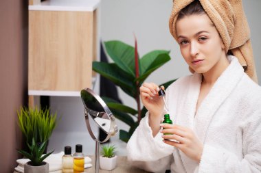 Sevimli kız banyoda yüzüne makyaj yapıyor.