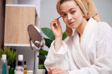 Sevimli kız banyoda yüzüne makyaj yapıyor.