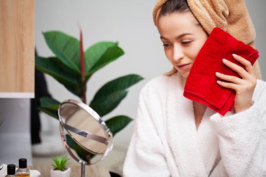 Kadın duş aldıktan sonra yüz havlusunu siler.