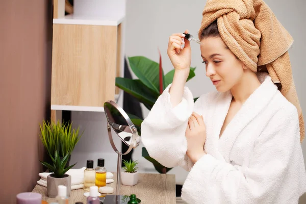 Schattig meisje maakt make-up op het gezicht in de badkamer — Stockfoto