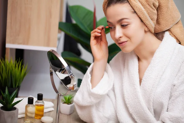 Sevimli kız banyoda yüzüne makyaj yapıyor.