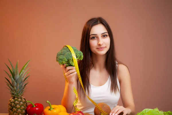 Retrato de jovem mulher bonita com legumes, frutas e fita métrica — Fotografia de Stock