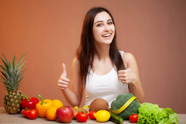 Retrato de jovem mulher bonita com legumes, frutas e fita métrica — Fotografia de Stock