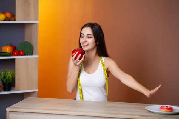 Retrato de uma jovem menina bonita que faz uma escolha entre comida saudável e prejudicial — Fotografia de Stock