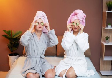 Kafasında havluyla evde spa tedavisi yapan iki kız arkadaş.