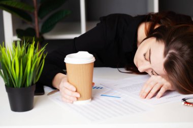 Ofisteki bilgisayarın başında çalışan yorgun kadın.