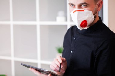 Koronavirüsten korunmak için ofiste maske takan bir adam.