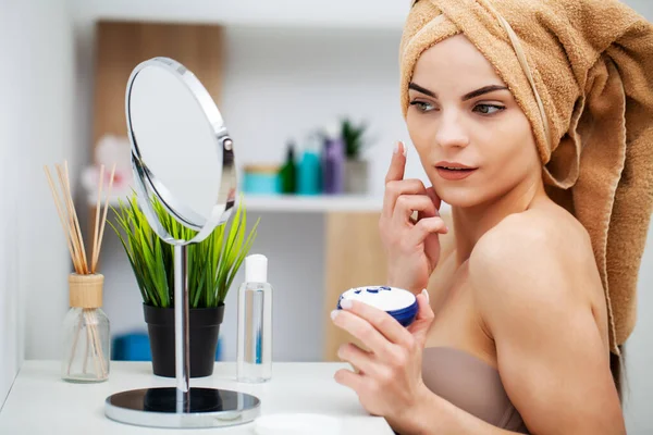 Aranyos lány tesz arckrémet a fürdőszobában — Stock Fotó