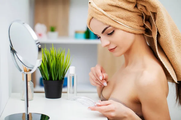 Schattig meisje zet make-up op het gezicht in de badkamer — Stockfoto