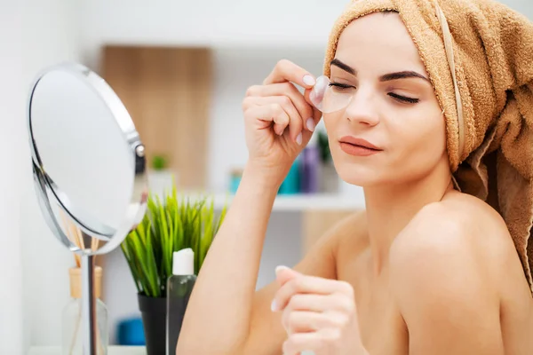 Linda chica pone parches bajo los ojos en el baño — Foto de Stock