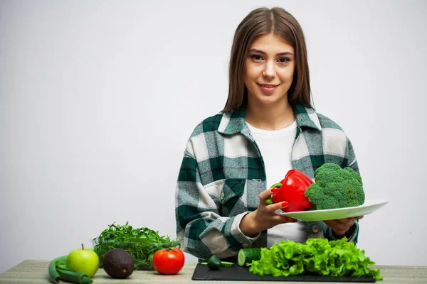 Concepto de alimentación saludable y dieta niña sosteniendo verduras en la pared blanca de fondo — Foto de Stock