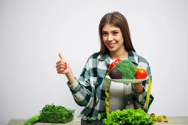 野菜を背景にした健康的な食事とダイエットの女の子の概念白い壁 — ストック写真