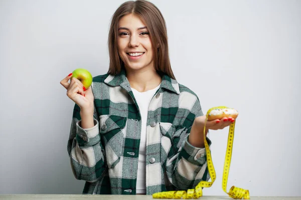 Chica hace una elección entre alimentos saludables y nocivos —  Fotos de Stock