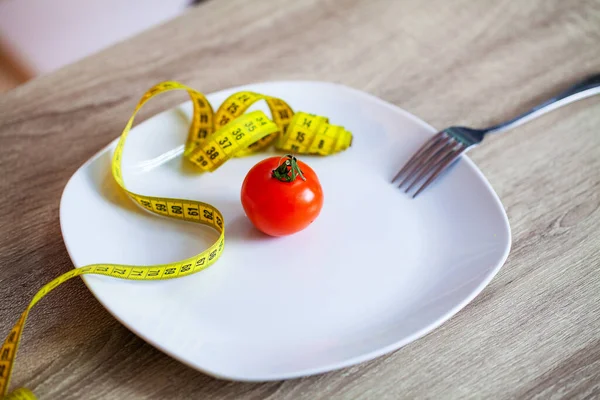 Concepto de sobrepeso, tomate y cinta métrica en un plato — Foto de Stock