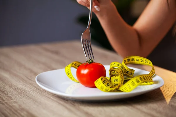 Concepto de sobrepeso, tomate y cinta métrica en un plato — Foto de Stock