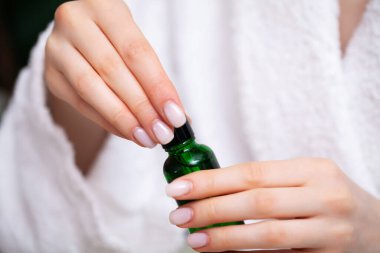 Kız yüz bakımı için losyon sürmüş.