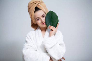 Kafasında havlu ve duş aldıktan sonra yeşil yaprak olan güzel bir kız.