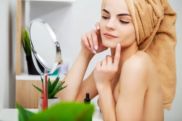 Pretty young woman puts makeup on the face in the bathroom