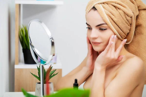 Pretty young woman puts makeup on the face in the bathroom — Stock Photo, Image