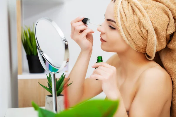 Mujer bastante joven pone maquillaje en la cara en el baño — Foto de Stock