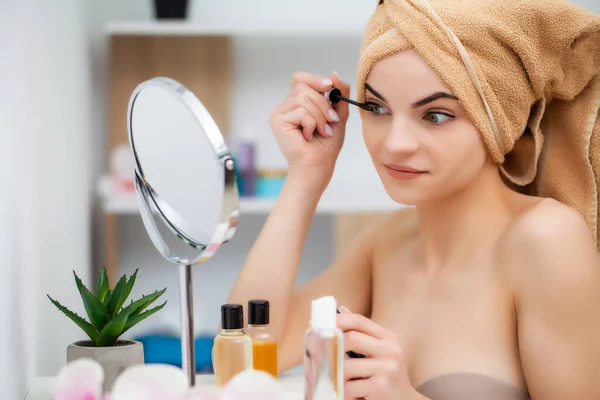 Bella giovane donna mette il trucco sul viso in bagno — Foto Stock