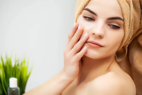 Hübsche junge Frau legt im Badezimmer Pflaster unter die Augen — Stockfoto