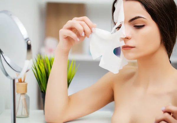 Wanita cantik dengan masker wajah di kamar mandi — Stok Foto