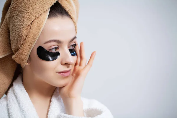 Pretty young woman puts patches under the eyes in the bathroom — Stock Photo, Image