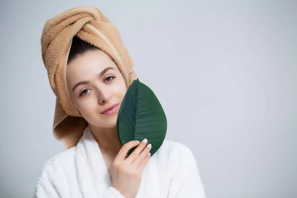 Ładna dziewczyna z ręcznikiem na głowie i zielonym liściem po wzięciu prysznica — Zdjęcie stockowe