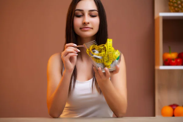 Mujer linda en una dieta sosteniendo un plato lleno de cinta —  Fotos de Stock