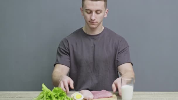 Сильний спортсмен з їжею, багатою білком на обробній дошці на столі — стокове відео