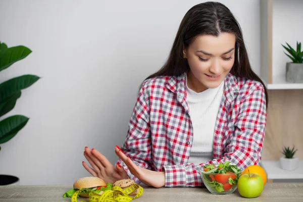 Mulher bonito faz uma escolha entre alimentos saudáveis e prejudiciais — Fotografia de Stock