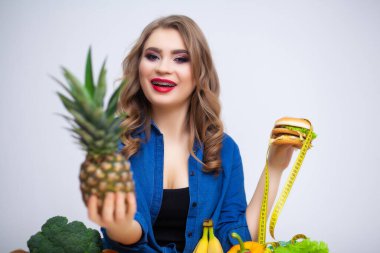 Şirin bir kadın sağlıklı ve zararlı yemek arasında seçim yapar.