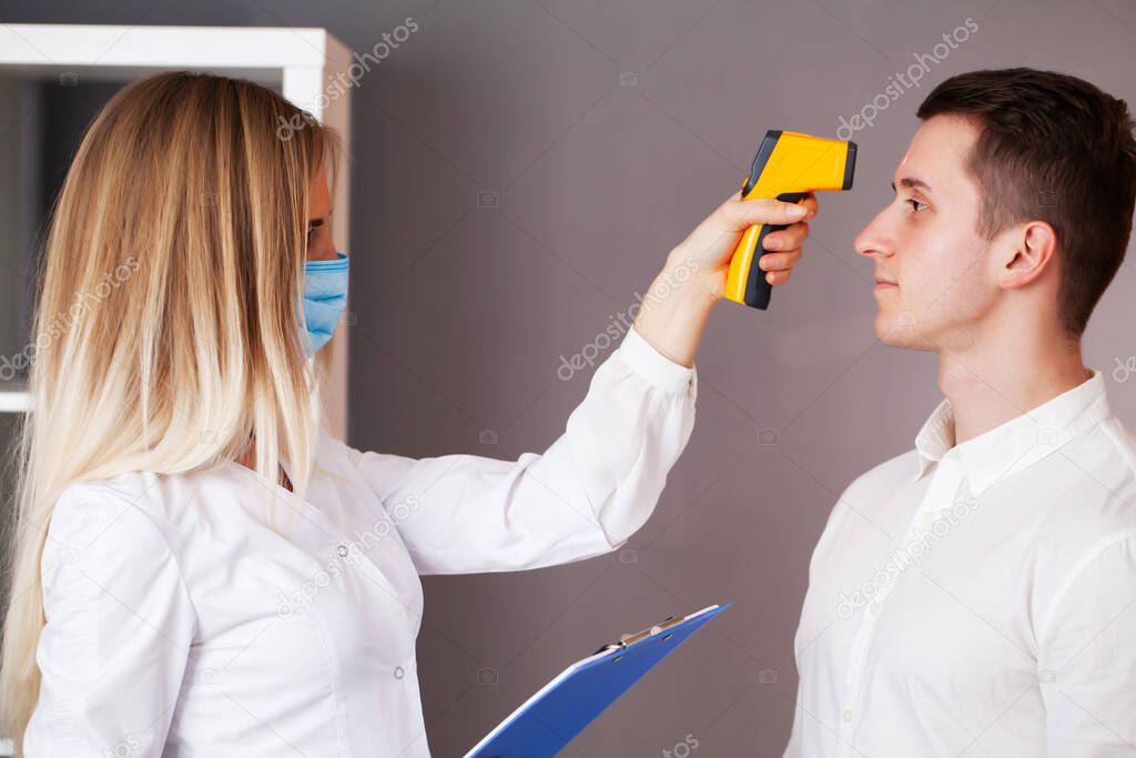 Doctor measures the temperature of a patient during an epidemic covid-19