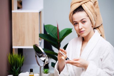 Kız yüz bakımı için losyon sürmüş.