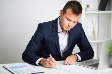 Ceketli sağlam bir işadamı şirketin ofisinde belgelerle çalışıyor.