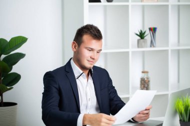 Ceketli sağlam bir işadamı şirketin ofisinde belgelerle çalışıyor.