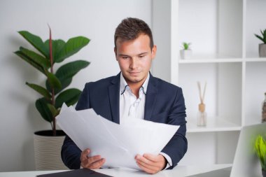 Ceketli sağlam bir işadamı şirketin ofisinde belgelerle çalışıyor.