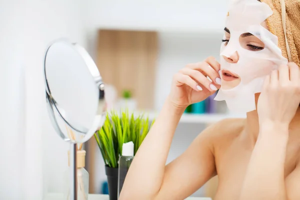 Seorang wanita menggunakan masker perawatan wajah di kamar mandi — Stok Foto