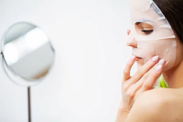 Seorang wanita menggunakan masker perawatan wajah di kamar mandi — Stok Foto