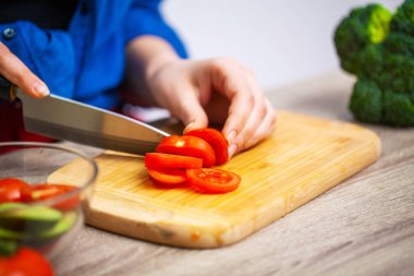 Kadın diyet salatası için domates dilimliyor.