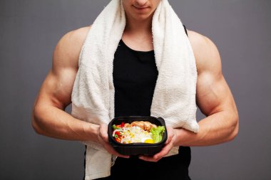 Spor beslenmesi için protein zengini yiyeceklerle dolu bir kutu taşıyan bir adamın yakın çekimi.