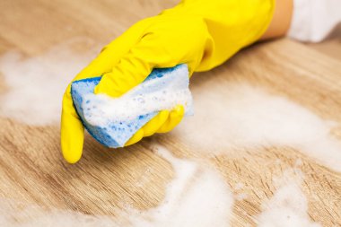 Ofisteki tozu sarı eldivenlerle silen işçi ellerini kapat.