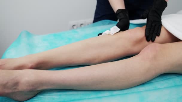 Młoda kobieta otrzymuje laserową depilację nóg w salonie piękności — Wideo stockowe