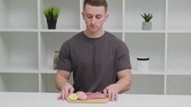 Sporcu bir adam, spor beslenmesi için protein zengini gıdalarla dolu bir tahtayı tutuyor..