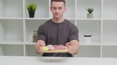 Sporcu bir adam, spor beslenmesi için protein zengini gıdalarla dolu bir tahtayı tutuyor..
