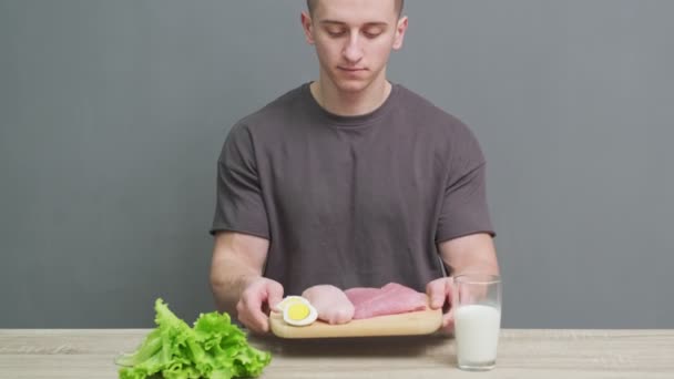 Sporcu bir adam, spor beslenmesi için protein zengini gıdalarla dolu bir tahtayı tutuyor.. — Stok video