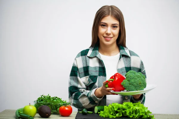 野菜を背景にした健康的な食事とダイエットの女の子の概念白い壁 — ストック写真