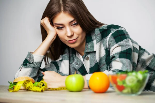 Femme fait un choix entre des aliments sains et nocifs . — Photo